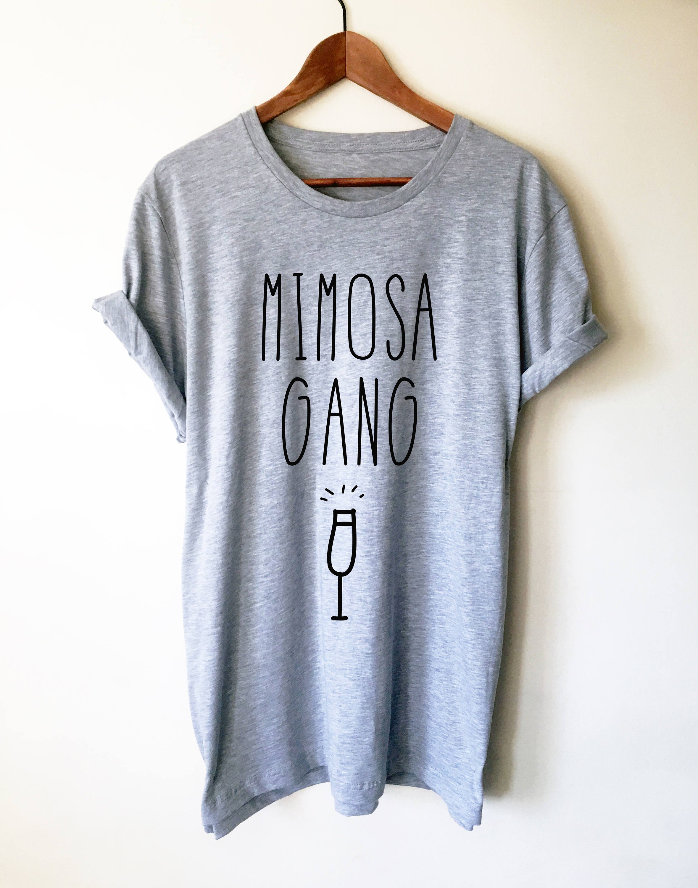 Mimosa Gang unisex t-shirt in heather grey, hanging on a wood hanger